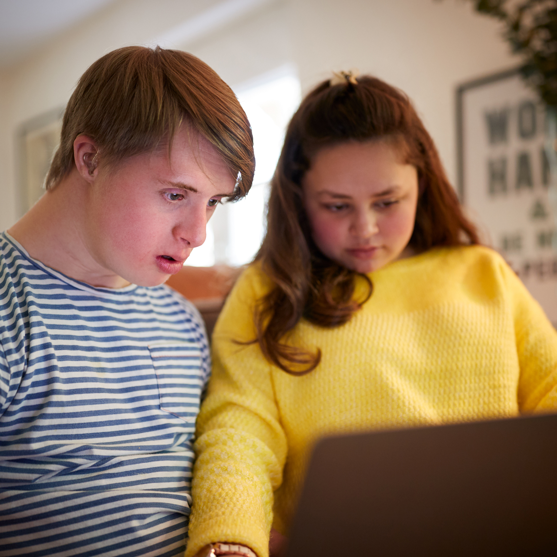 33105831 Young Downs Syndrome Couple Sitting On Sofa Using Laptop