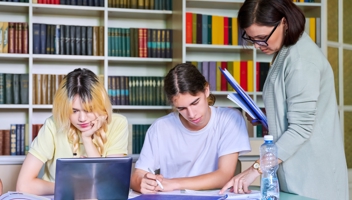 55224012 Girls Teenage Students Studying In Library With Teacher