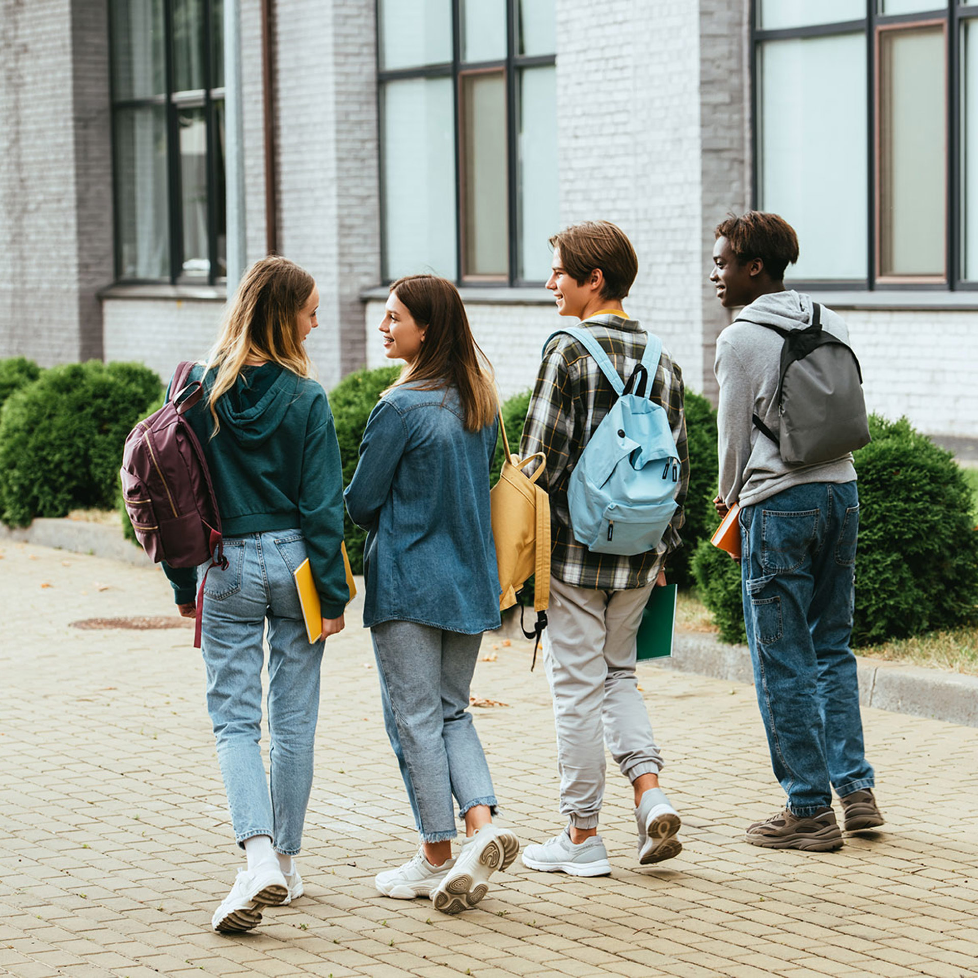 42823841 Back View Of Smiling Teenagers With Backpacks Walking On